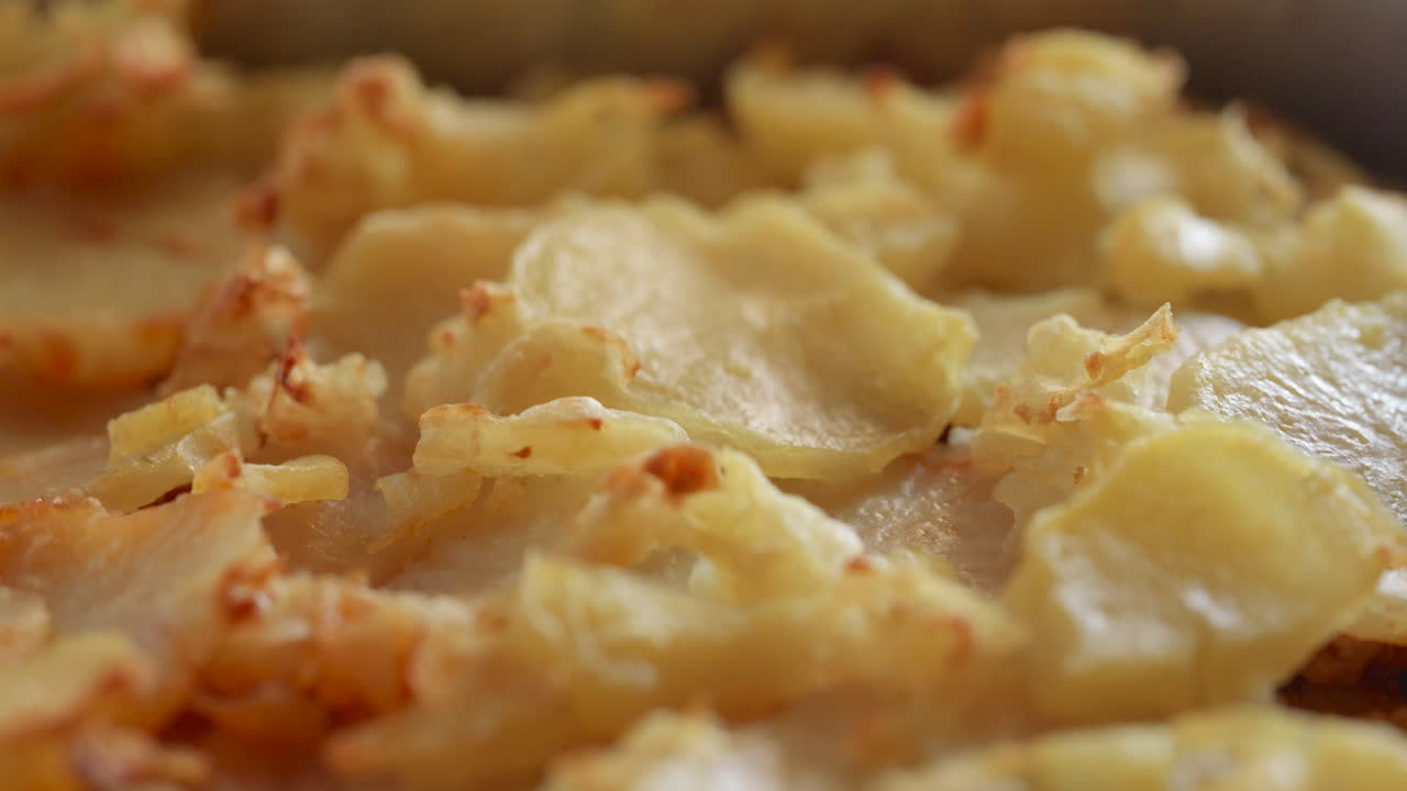 Close-up of oven-roasted potato slices with crispy edges. The camera moves steadily forward