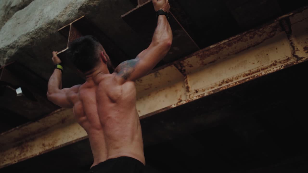 Pull-up strength training exercise - fitness man working out his arm muscles on outdoor beach gym doing chin-ups - pull-ups as part of a crossfit workout routine