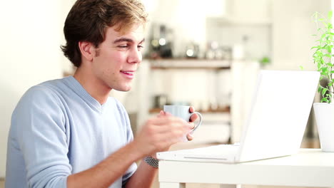 joven trabajando en una computadora portátil y bebiendo café