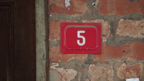red number 5 on a brick wall