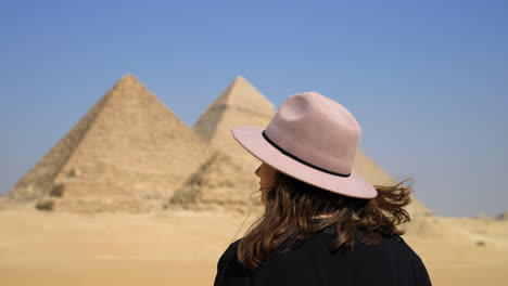 female tourist with purple hat looking at the great pyramid of giza in cairo, egypt at sunny day