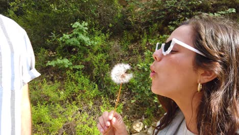 a woman blows a dandelion with her boyfriend in slow motion