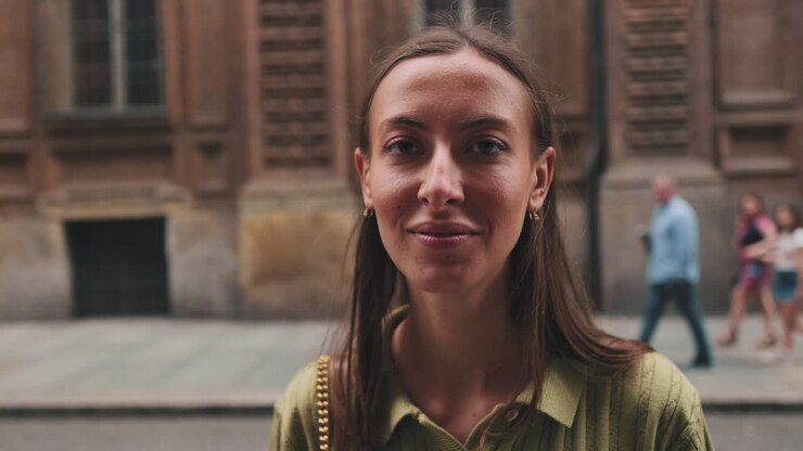 Giovane donna si gira e sorride alla fotocamera in una strada cittadina