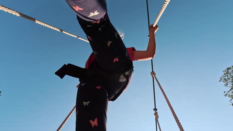 niña feliz jugando en la atracción de tarzán en el patio de recreo en el parque de atracciones