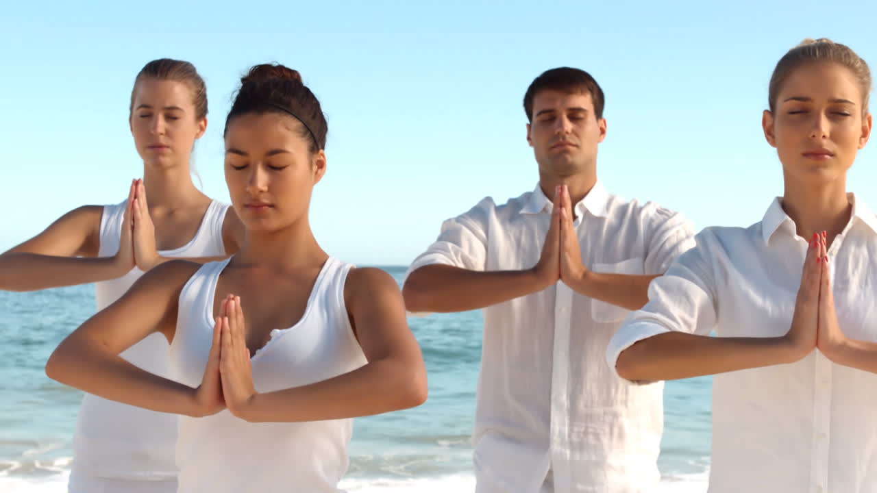 Persone sulla spiaggia che praticano yoga