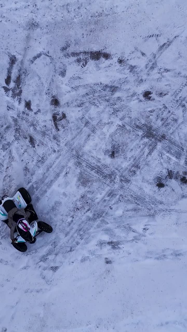 Veduta aerea di una persona che guida un quad su terreno innevato