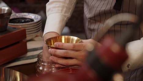 chef fills metal cup with green olives