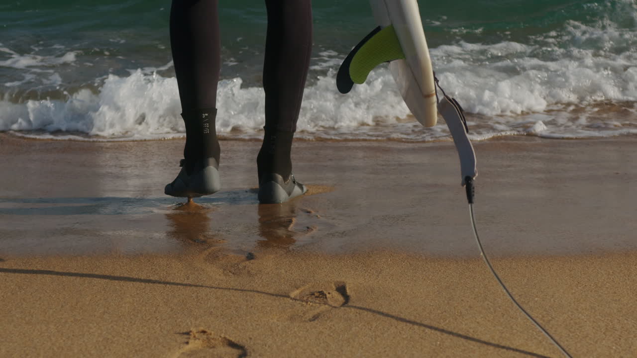Surfer man walking to the beach at sunset preparing for surfing training and search for waves in Barcelona, spain, water, ocean exercise in sea with board, athletic male holiday or travel in vacation