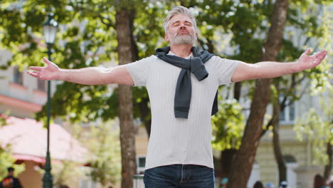 keep calm down, relax mature man meditating praying eyes closed making a deep breath in city street