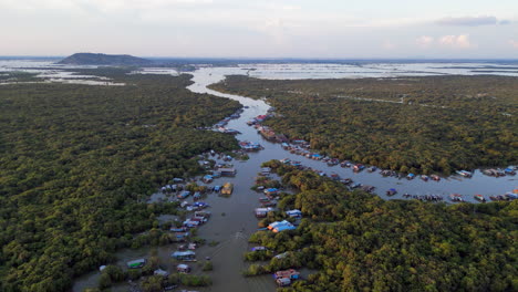 local fisherman drives boat through river village in cambodia