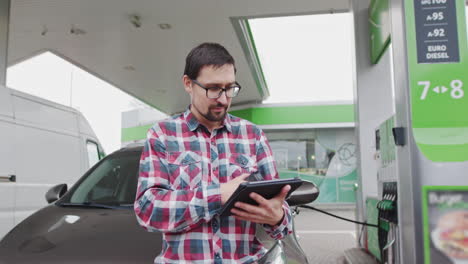 man using tablet at gas station