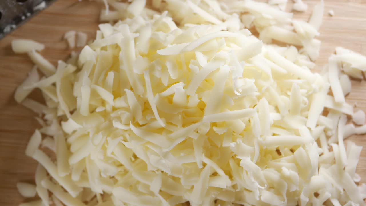 queso triturado en una tabla de cortar de madera