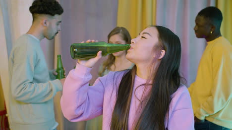 portrait of a happy young asian girl looking at the camera and drinking beer at home