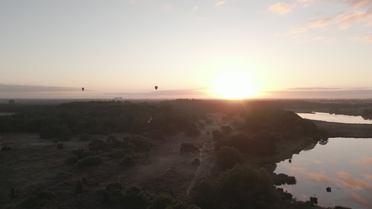 숲과 호수 위를 날아다니는 해가 뜨는 공기 풍선