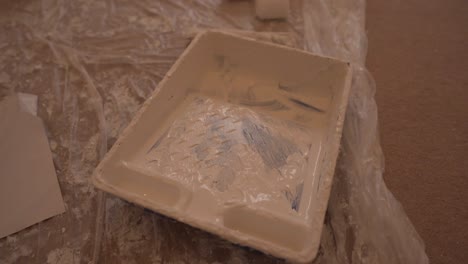 close view of white painting tray for paint mixture on the plastic cover floor