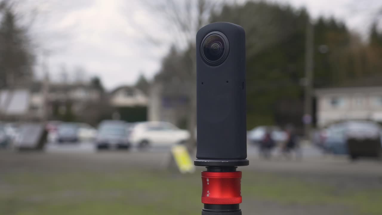 black Ricoh Theta V 360 camera on monopod to capture photos videos of park panorama