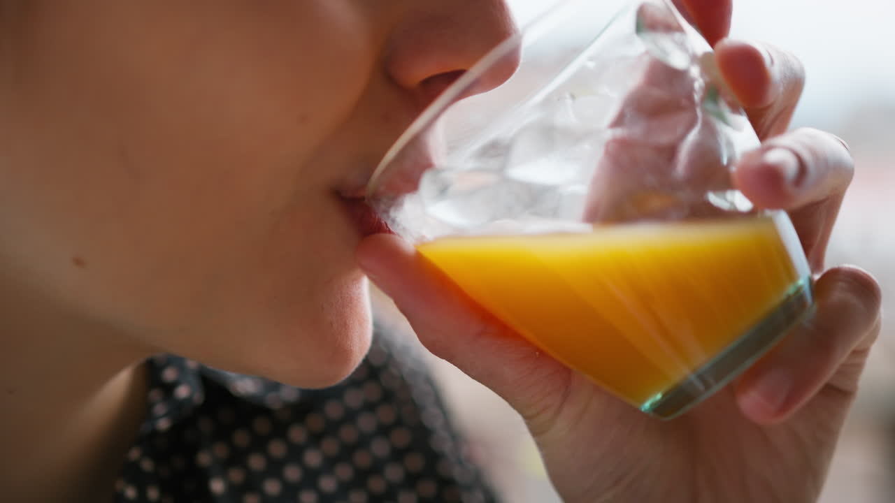 Donna beve succo d'arancia fresco al mattino per le vitamine.