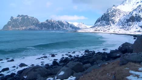 waves roll into a beautiful snow covered shoreline amidst fjords north of the arctic circle in lofoten islands norway