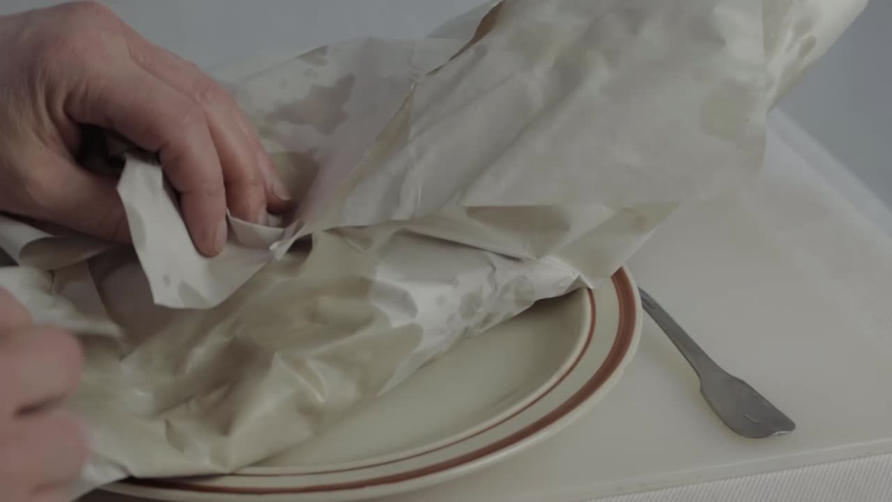 Hand unwrapping fish and chips wrapped in paper medium shot