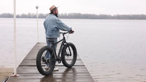 man with fat tire bike on a dock by a river