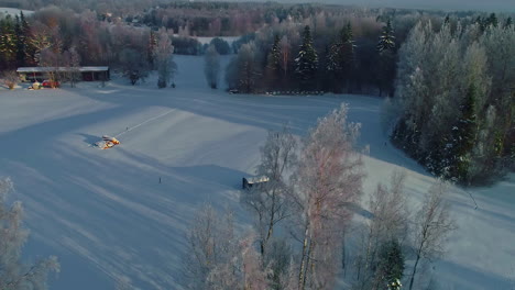 circular drone footage of a snowy landscape with huts and some houses in the distance