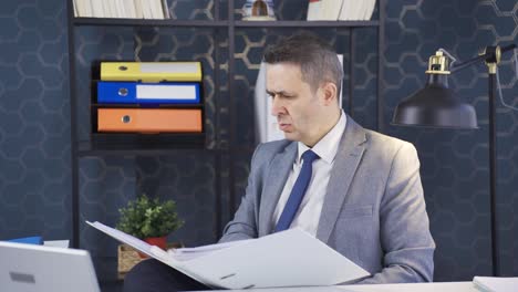 serious and focused mature businessman looking at paperwork files in office.