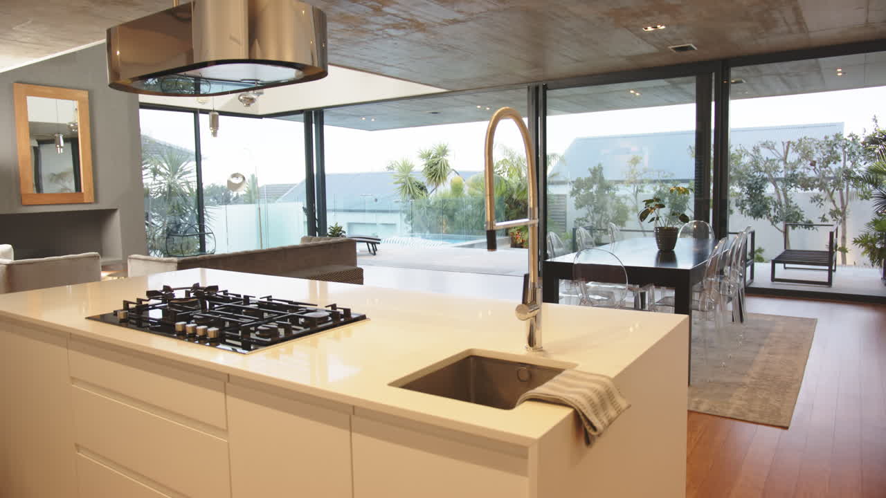 Cozinha moderna com fogão a gás e pia, com vista para uma espaçosa área de estar e jantar, em casa.