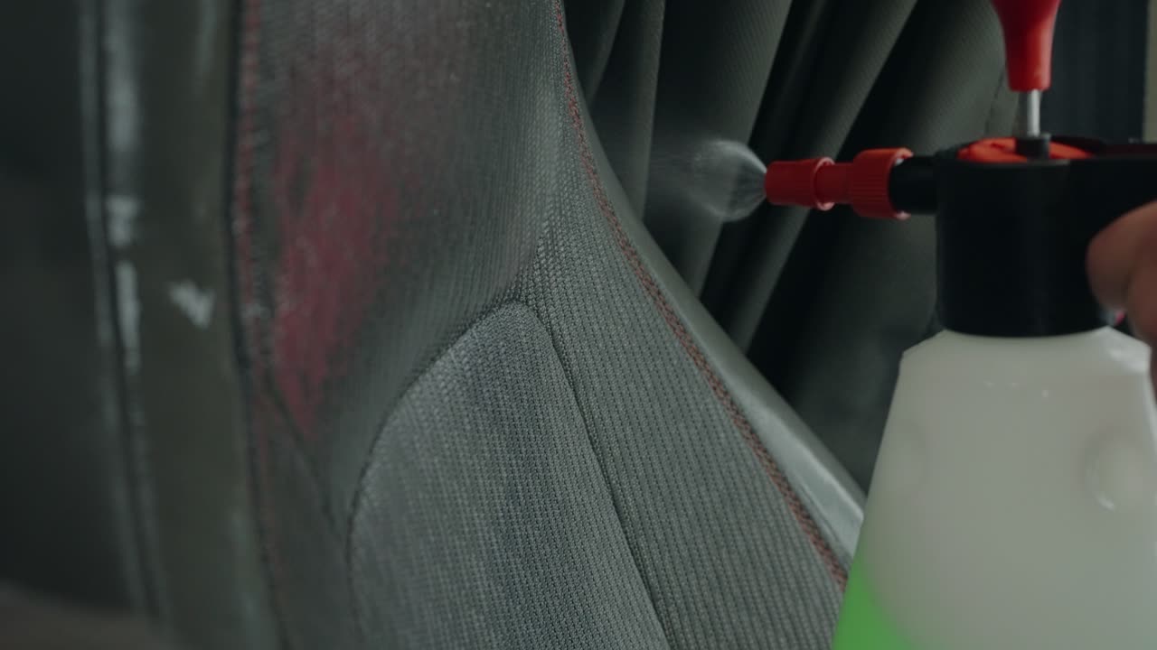 limpieza profunda y cercana del asiento de tela del automóvil utilizando un pulverizador químico