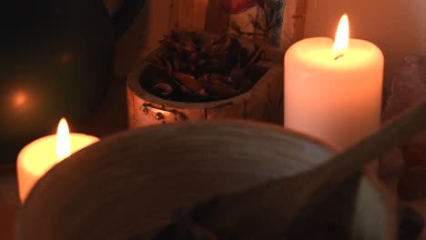 relaxing background detail shot of an herbal tea shop, with candles with flickering flames, herbs, a wooden bowl and some dust flying around