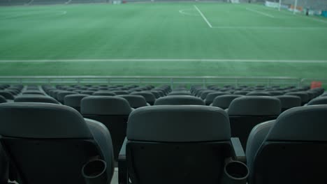 empty seats of football stadium with green grass in background