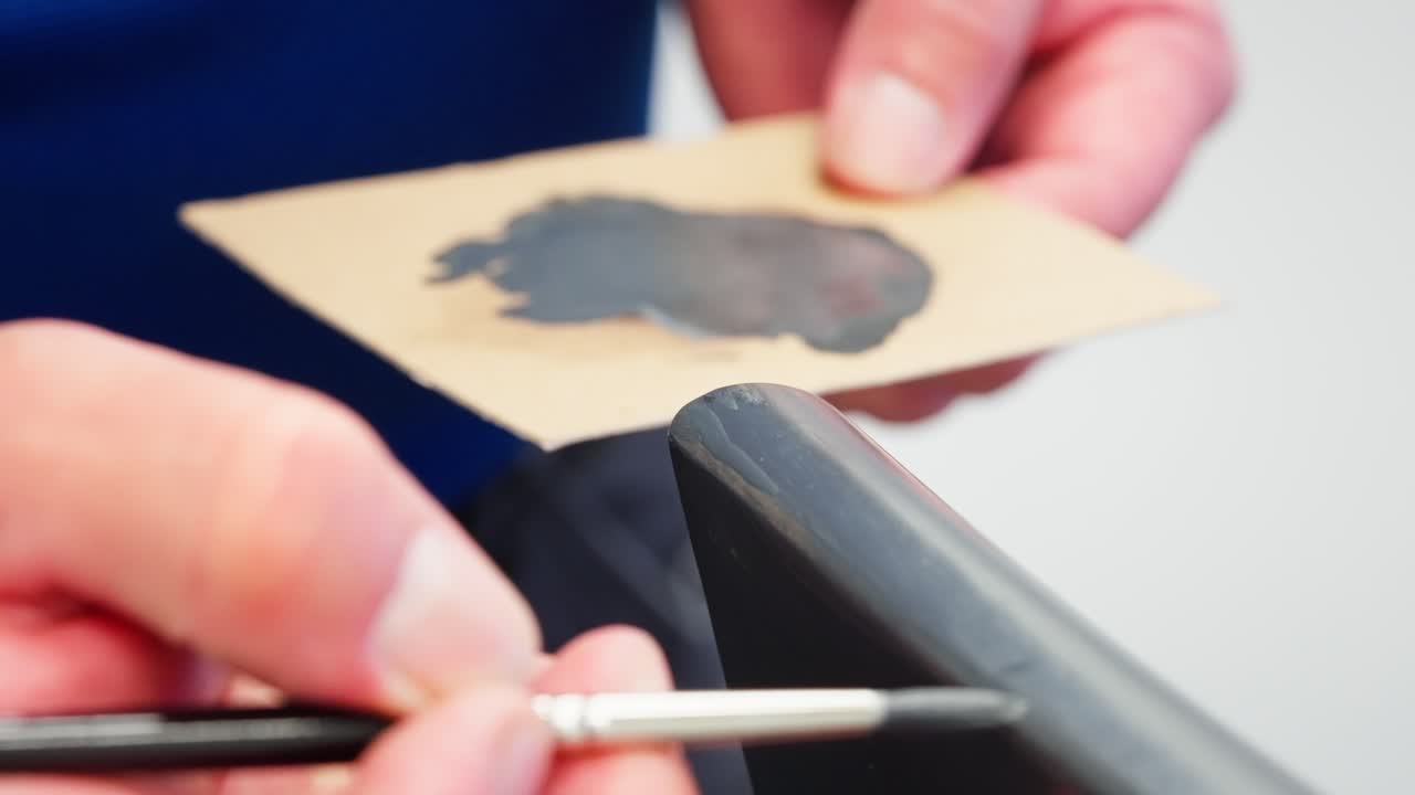 Meticulous painting of grey chair corner with small brush and mix palette