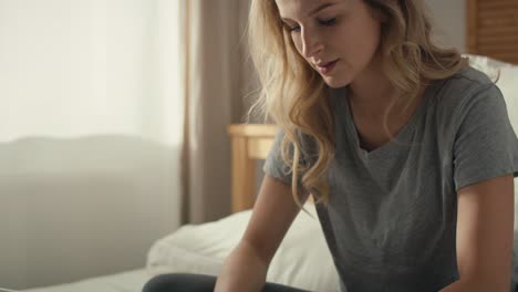 caucasian woman sitting on the bed and using the laptop at morning.