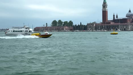 an ambulance boat speeding along a canal with st mark's square in background at venice, italy.