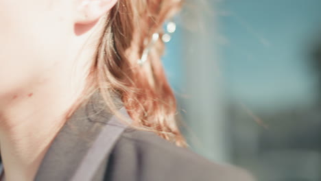 young lady frustrated during phone call after work, about to lower phone while exiting office building, dressed in formal outfit, glass door reflects urban setting with vehicles in background