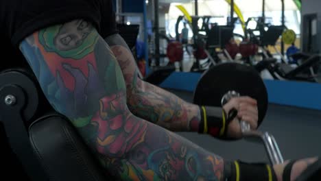 man with colorful tattoos working out bicep curls in gym