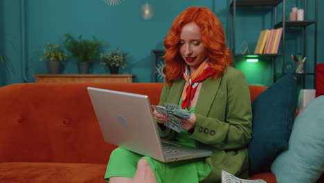 Smiling-happy-woman-counting-money-cash-and-use-laptop-pc-calculate-domestic-income-earnings-at-home