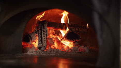 firewood burning stone oven at italian restaurant kitchen. hot fire in stove.