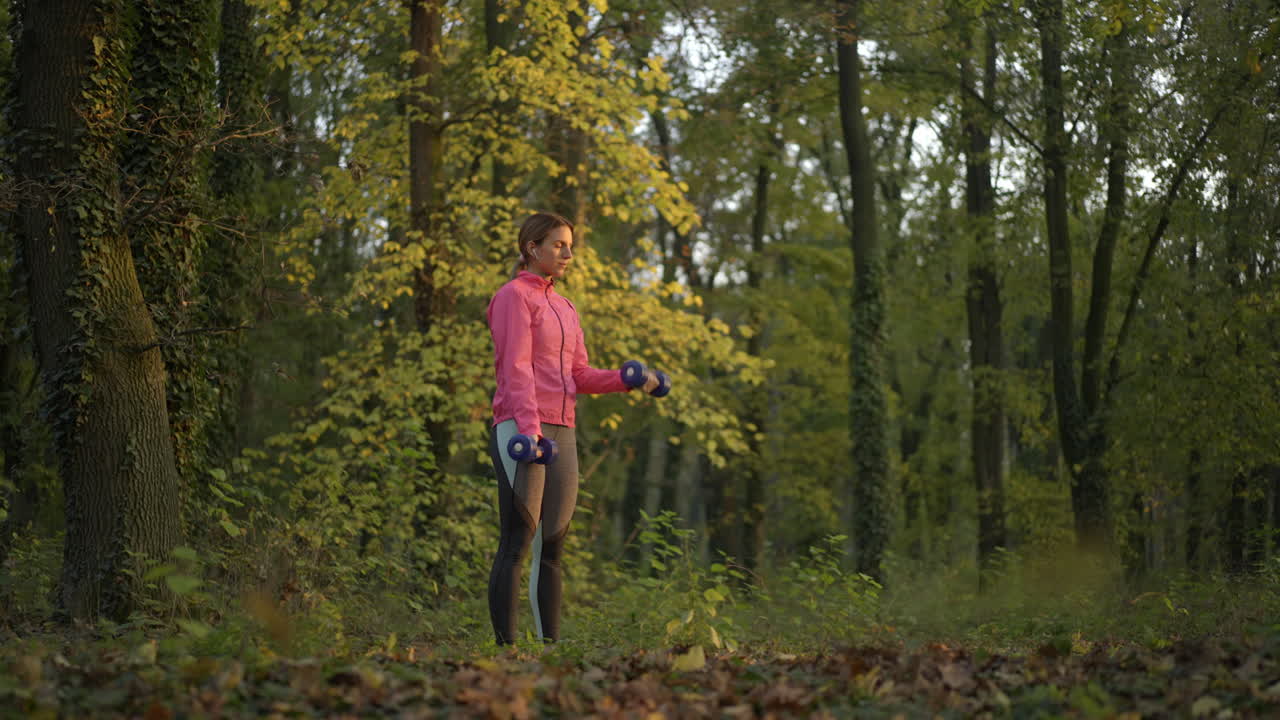 Woman Exercising with Dumbbells in a Forest