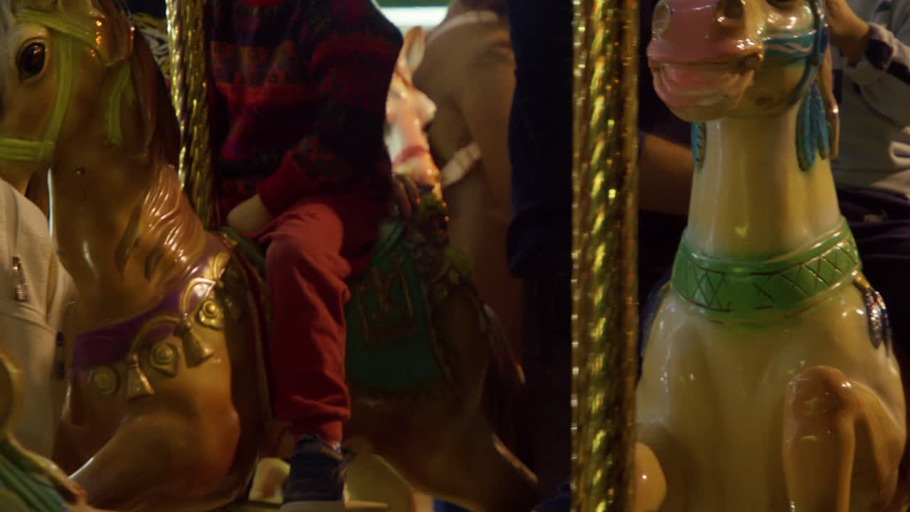 Carousel horses with moving kids on in slow motion at night