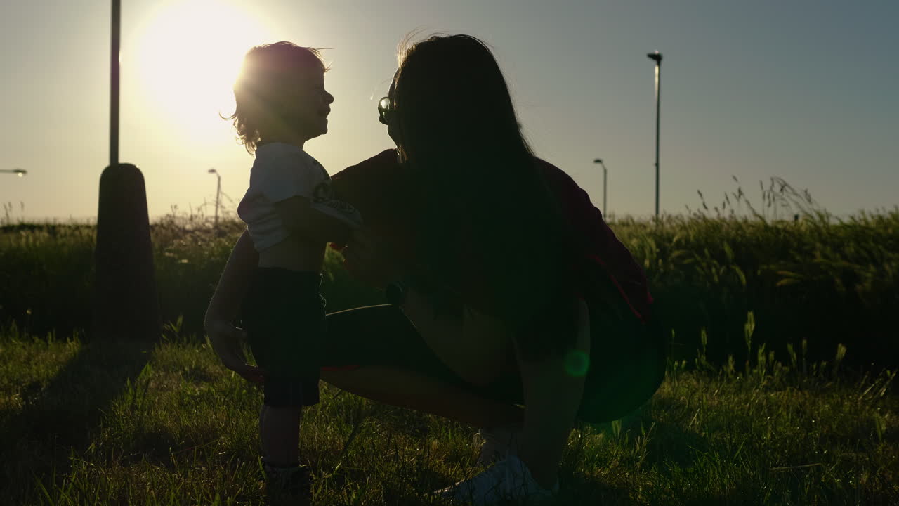 Silhouette of mother tickling son and him giggling and laughing with joy