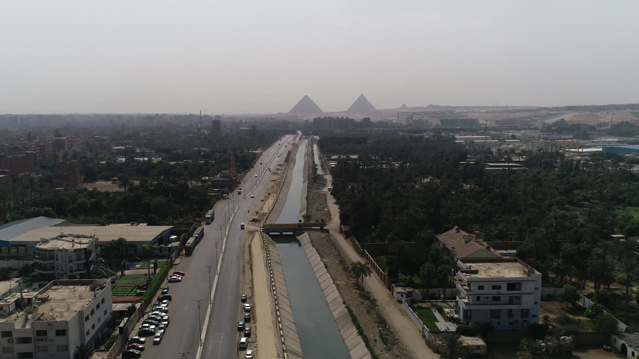 pista de disparo aéreo hacia fuera y subiendo para las pirámides de egipto en giza en el fondo de una rama del río nilo en el primer plano rama maryotya con las tierras verdes