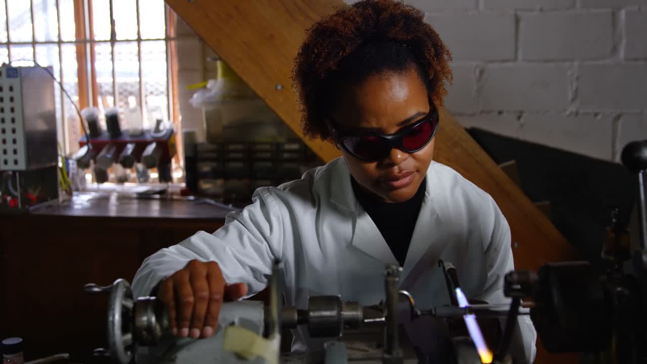 Front view of black female worker blowing glass in glass factory 4k