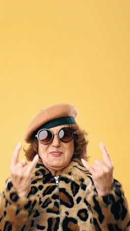 cool elderly woman in leopard print and beret making rock on gesture