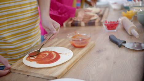 Diverse-group-of-teenage-friends-cooking-and-making-pizza-in-kitchen,-slow-motion