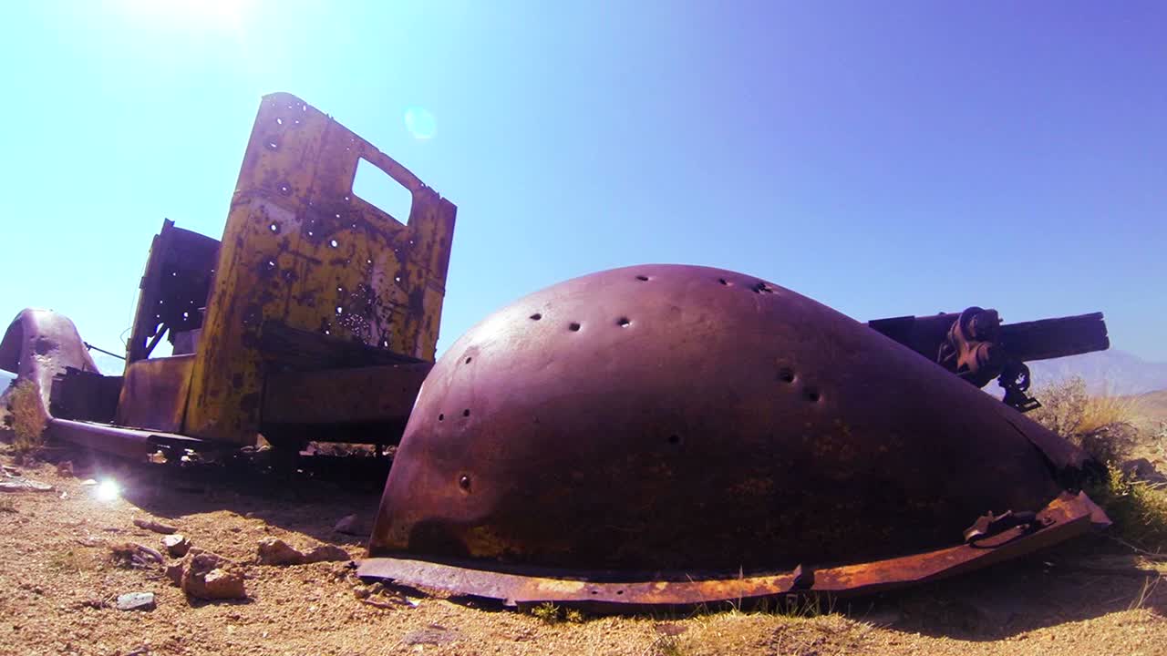 Dolly shot beside an abandoned pickup truck in the desert sun