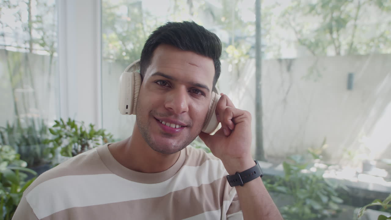 Indian Man Listening Music Using Headphones, Looking at Camera