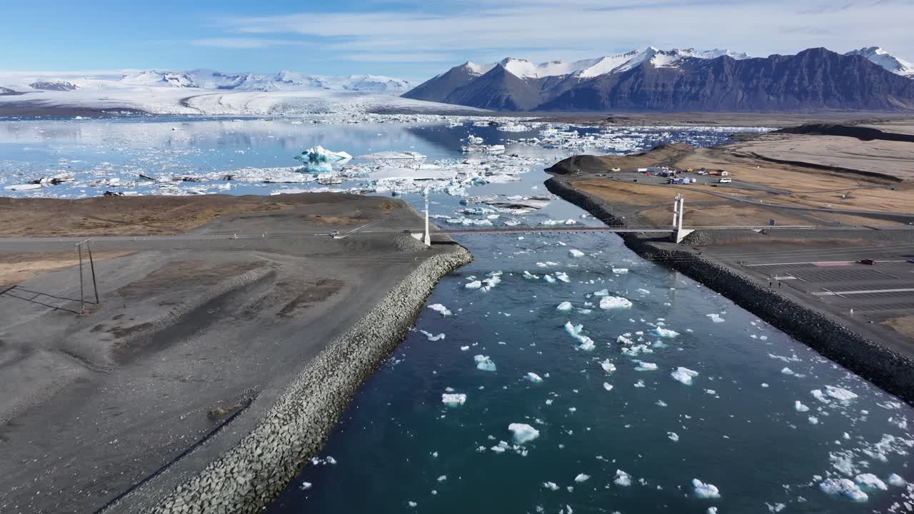 아이슬란드의 푸르키즈색 빙하 강은 눈 인 산과 반이는 빙산으로 둘러싸인 특이한 다리 에서 흐른다.