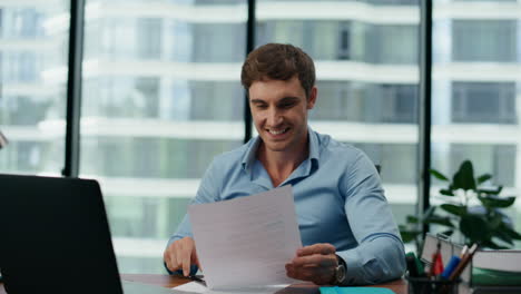 hombre emocionado leyendo el informe financiero sentado en la oficina de cerca. gerente regocijándose.