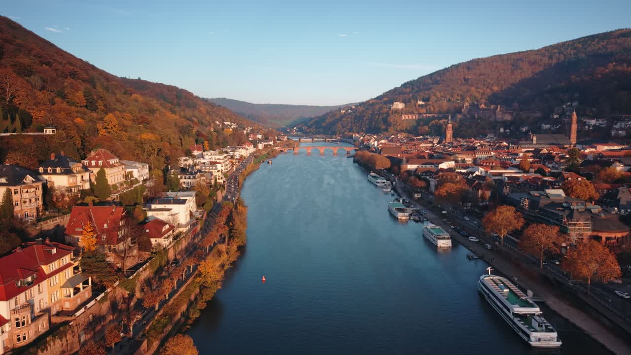 Drone Tracking Shot af rohold og flodkrydstogtskibe på Neckar-floden med Heidelberg Slot og den gamle bro om efteråret