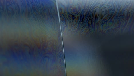 colorful streaks of lines on surface of soap bubble's surface: macro abstract